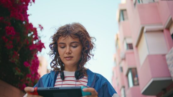 Jeune femme jouant à la console nintendo switch marchant dans une rue d'été, gros plan