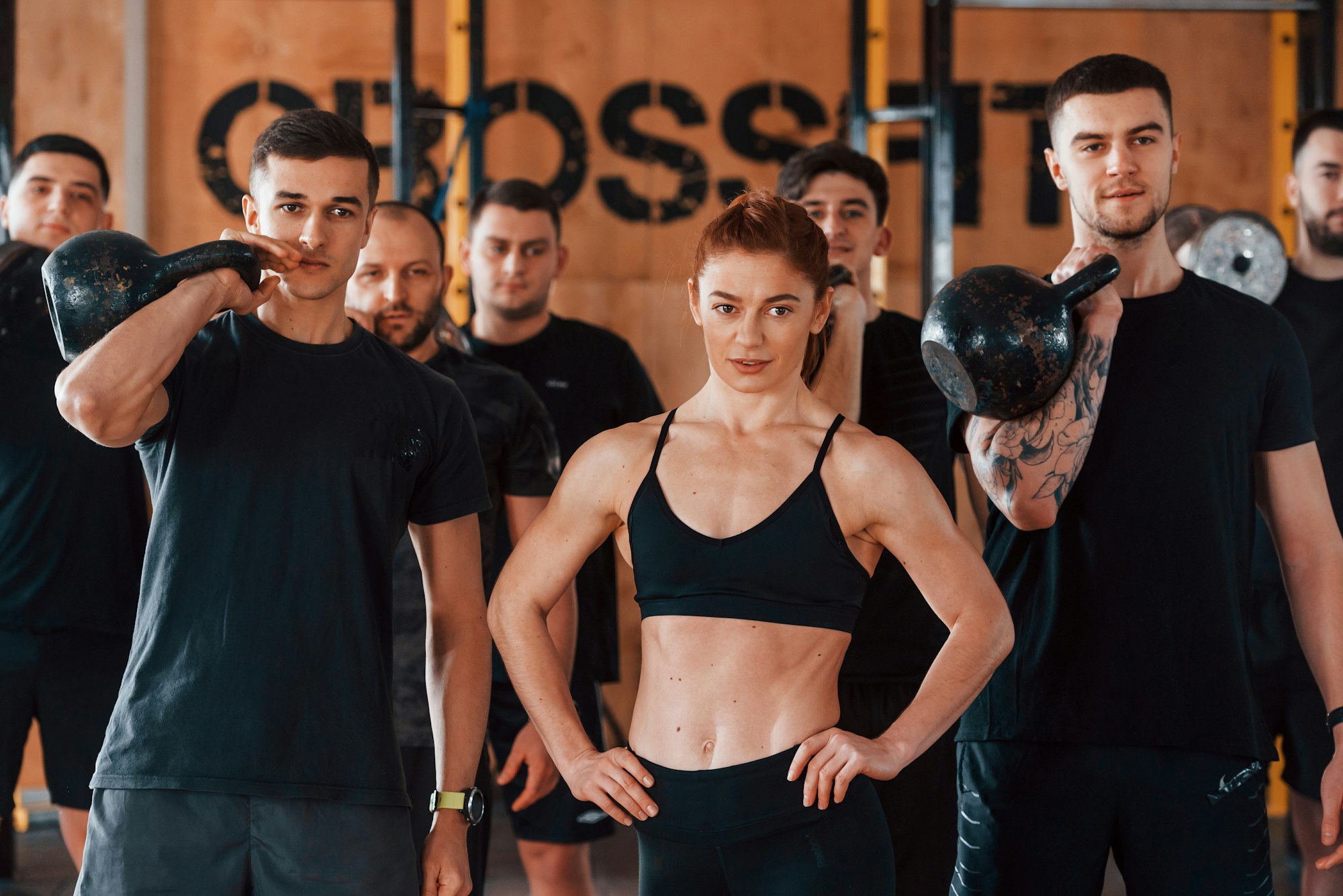 Posing for a camera. Group of young sportive people have crossfit day indoors in gym