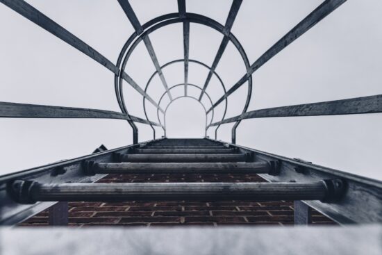 Vue en contre-plongée d'un escalier de secours en métal sur un mur de briques d'un bâtiment avec une cage de sécurité en acier.